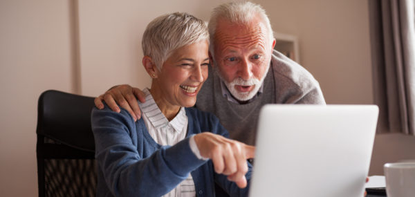 Shows an older couple sitting in front of a laptop