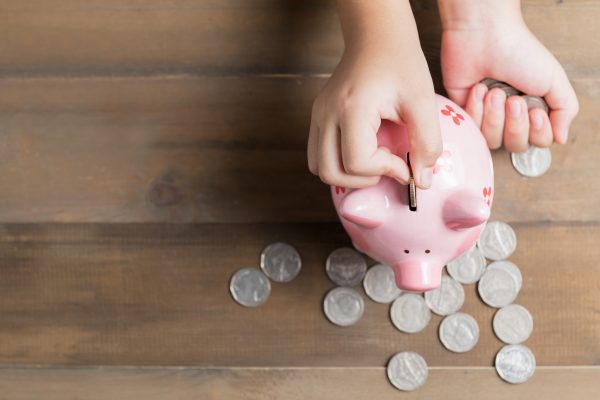 Child Placing Coin in a Piggy Bank