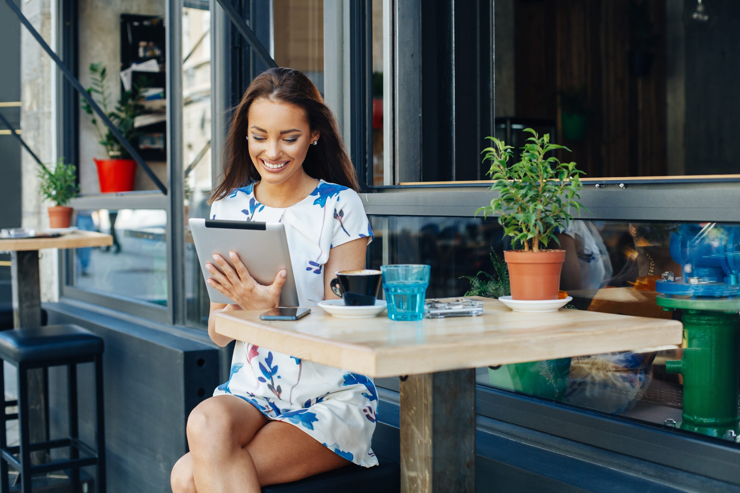 Young woman looking at a tablet while sitting outside at a cafe.