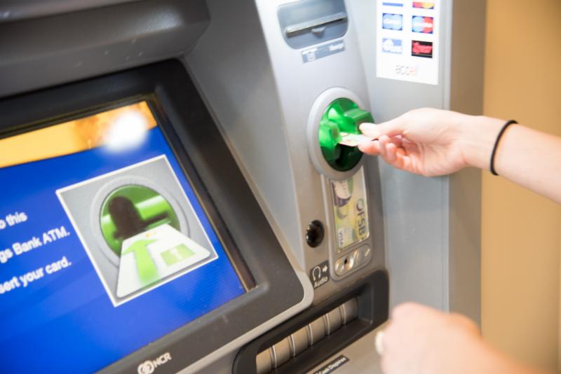 Woman inserting debit card into ATM