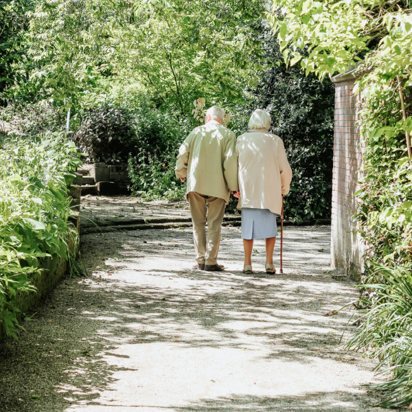 Elderly couple walking down a wooded path together