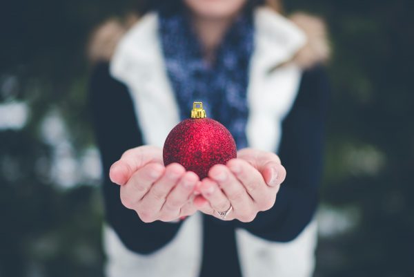 Season of giving image of woman holding ornament.