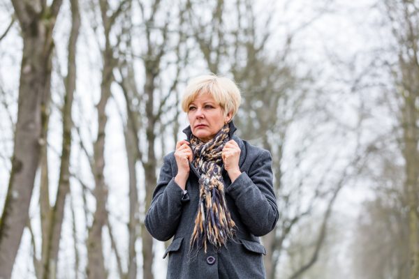 Older woman standing in the woods with her winter coat