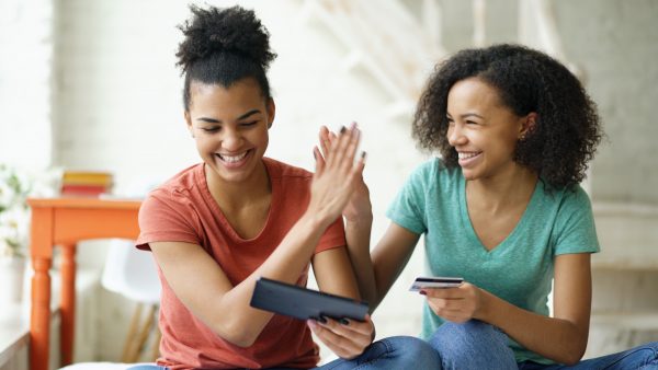 Two friends looking at tablet and giving a high-five.