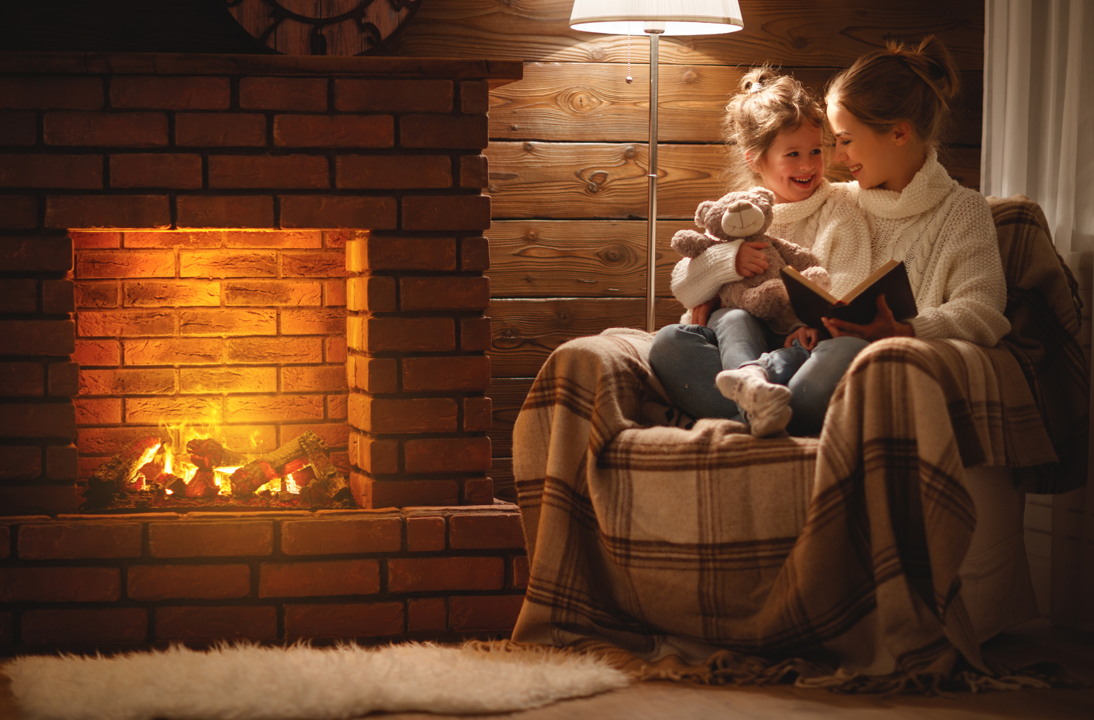 Photo of mother and daughter sitting in front of fireplace. 