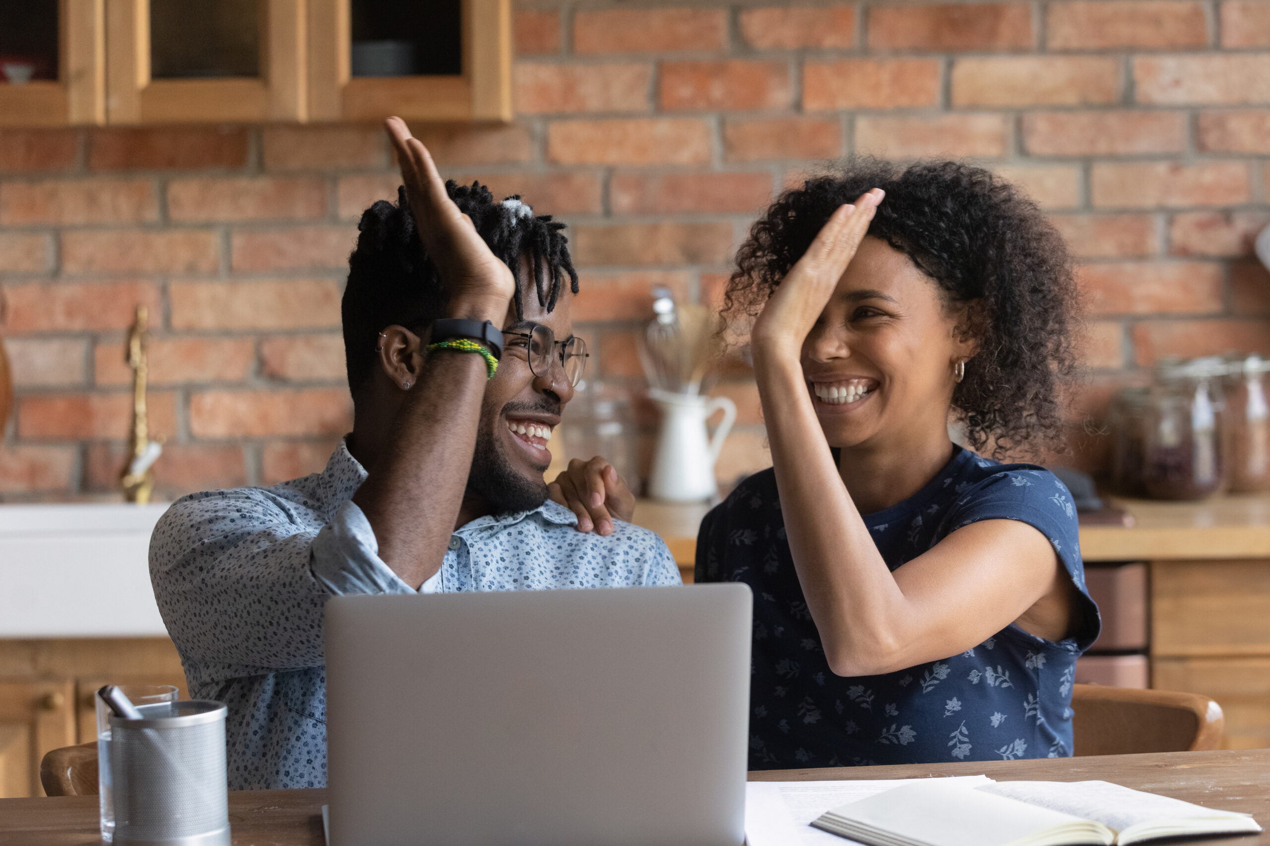Photo of an African American Couple sitting in front of a computer and giving a high-five.